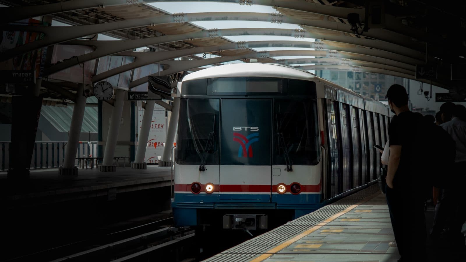 A BTS Skytrain arriving at a Bangkok station platform