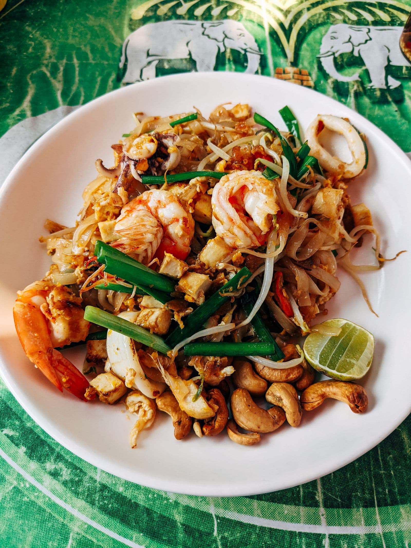 A plate of pad thai topped with shrimp and cashews