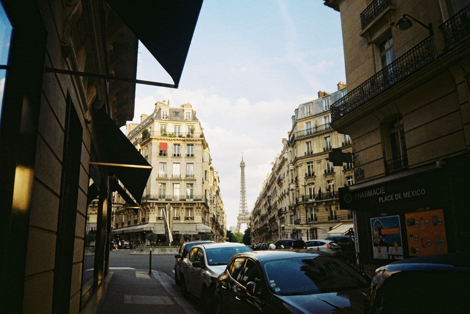 The Eiffel Tower seen between Haussmann buildings on a Paris street
