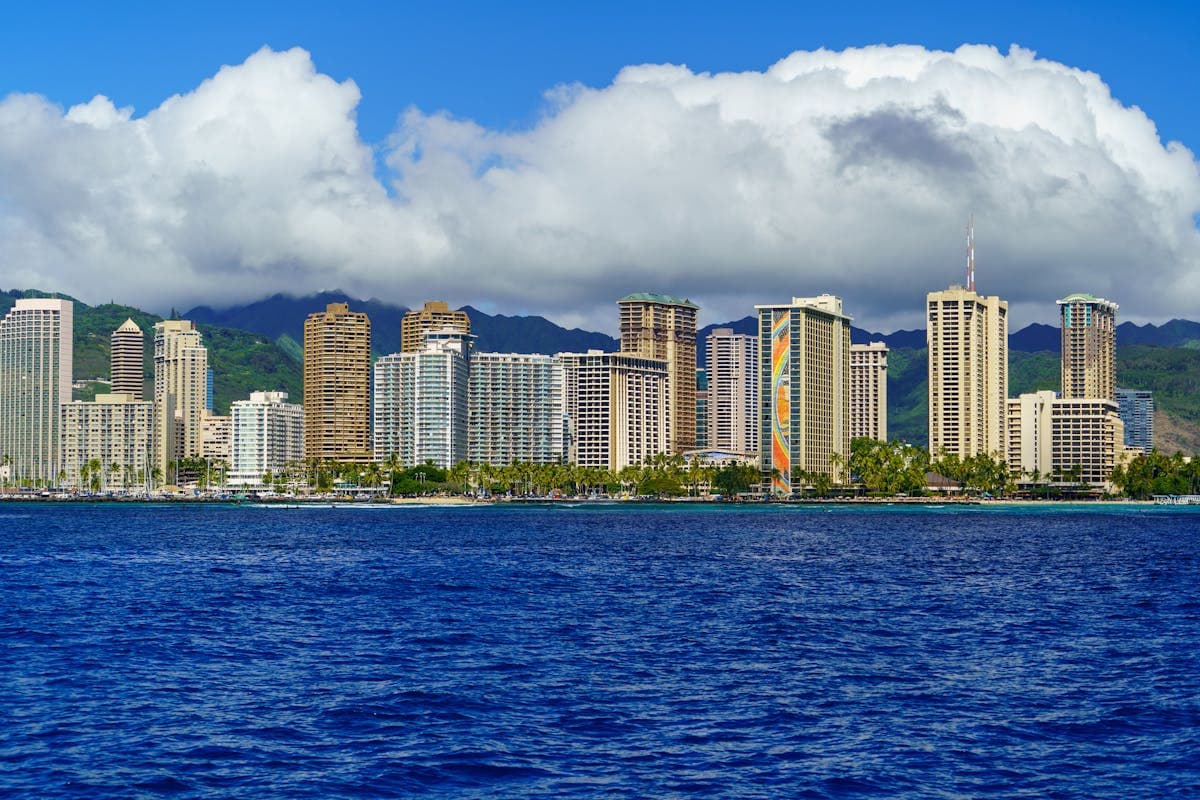 Honolulu skyline from the water, high-rise hotels, Koolau mountains, and blue sky