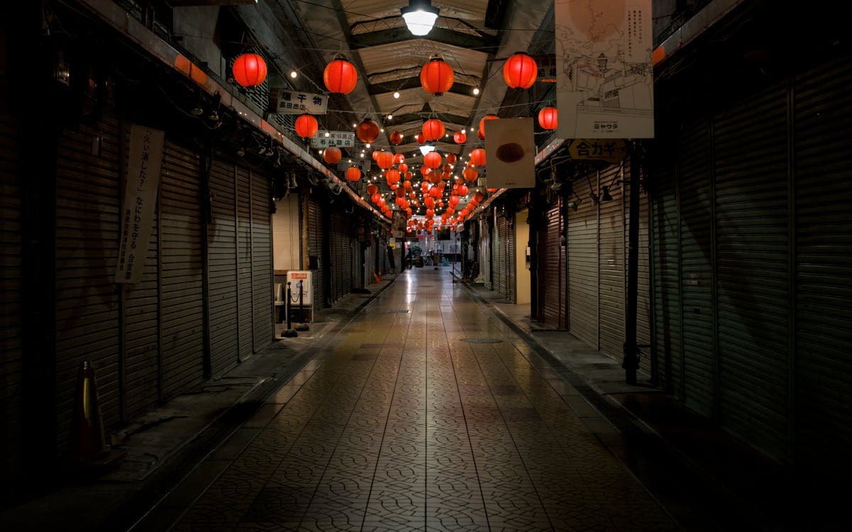 Kuromon Market arcade before opening, red lanterns hanging from the vaulted ceiling over shuttered stalls