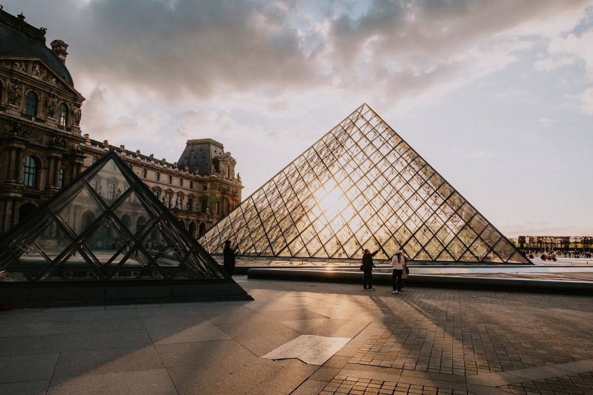 The Louvre Museum, I.M. Pei's glass pyramid glowing at golden hour, the world's most visited museum
