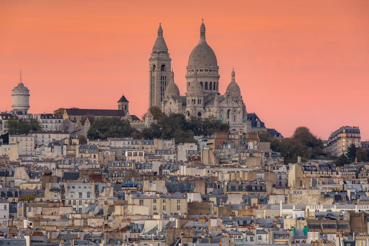 Montmartre and Sacré-Cœur Basilica, the white Byzantine dome glowing gold above Paris's rooftops at sunset