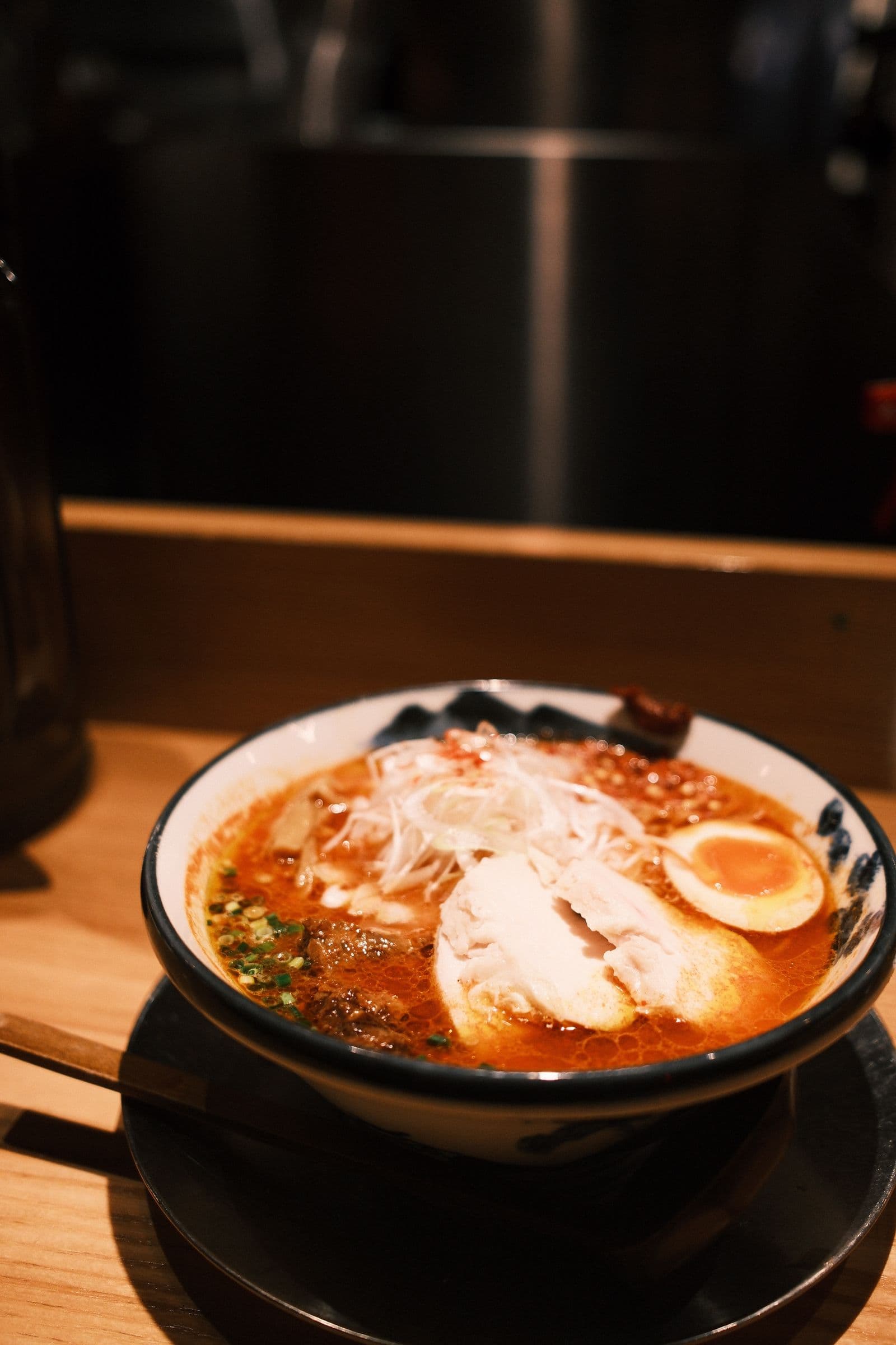 파 고명과 반숙 계란, 고기 고명을 올린 매운 라멘 한 그릇. 도쿄의 식당 카운터